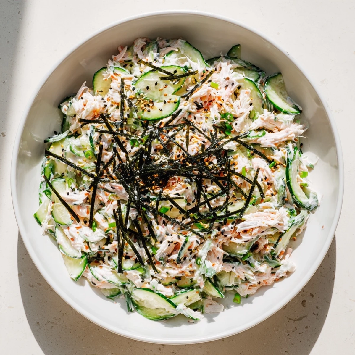 Vibrant California Roll Cucumber Salad topped with nori strips, scallions, and pickled ginger for a fresh Japanese-American appetizer.
