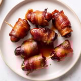 Maple syrup caramelizes on baked bacon-wrapped smokies, a delicious appetizer ready to serve.