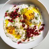 A close-up of steaming Çılbır showcasing perfectly poached eggs nestled over garlic yogurt.