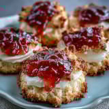 Clotted cream and strawberry jam thumbprint cookies with golden edges and sweet, creamy filling.