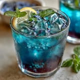 Butterfly Pea Flower Lemonade, a vibrant blue drink turning purple with ice.