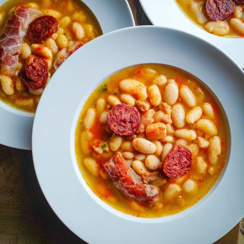 A steaming bowl of Budget Fabada Asturiana, featuring tender beans and hearty Spanish meats.
