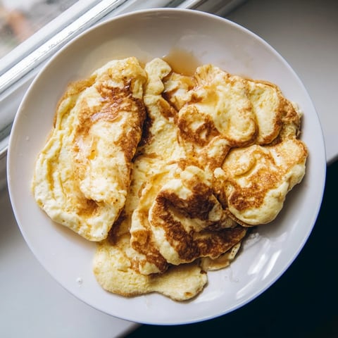 Golden, fluffy scrambled pancakes cooked in a skillet, ready to serve with maple syrup.