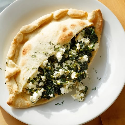 Golden, pan-fried Turkish Spinach & Feta Flatbread, showcasing a savory filling spilling out invitingly.