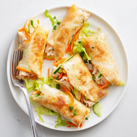 Golden, crispy Garlicky Pulled Chicken Wraps served warm with fresh herbs and lemon wedges.  