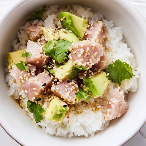 A vibrant Tuna Avocado Rice Bowl featuring flaky tuna, creamy avocado, and crisp cucumber on fluffy jasmine rice.