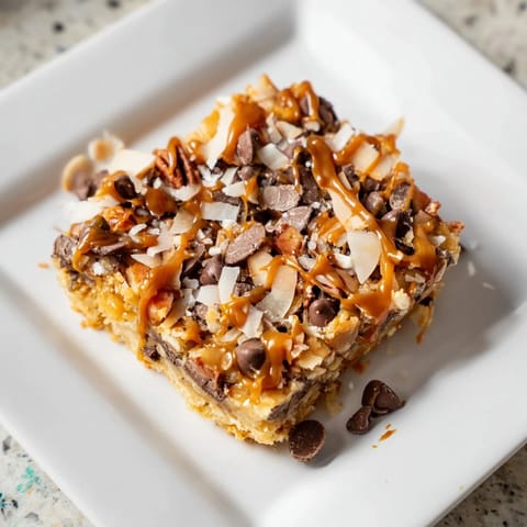 Golden-brown 7-Layer Magic Bars with a drizzle of glistening salted caramel, ready to serve and enjoy.