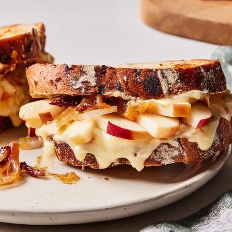 Sharp cheddar oozes from this Caramelized Onion, Apple & Cheddar Grilled Cheese, with sweet apple slices visible.