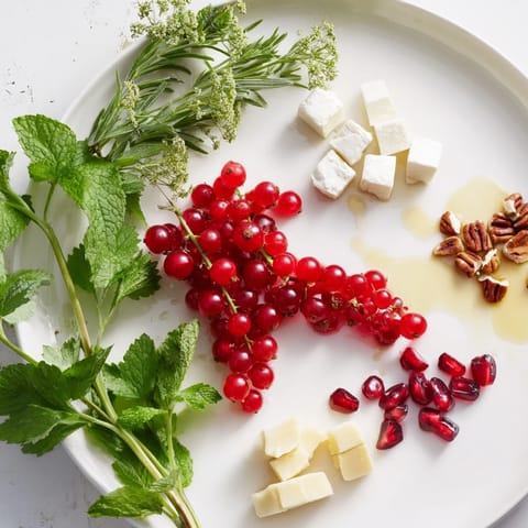 A beautiful holiday Holly Berry Cluster appetizer with red berries, goat cheese, and rosemary sprigs to share.