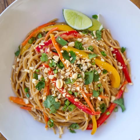 Vibrant plate of spicy peanut noodles with peanuts and cilantro, perfect for a quick dinner.
