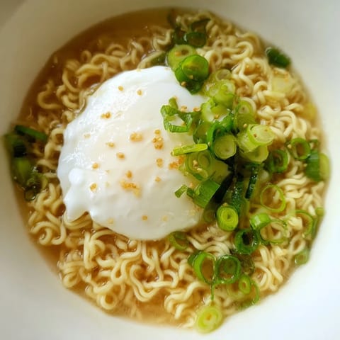 A close-up of upgraded instant ramen, showing the rich broth, melting butter, and soft egg.