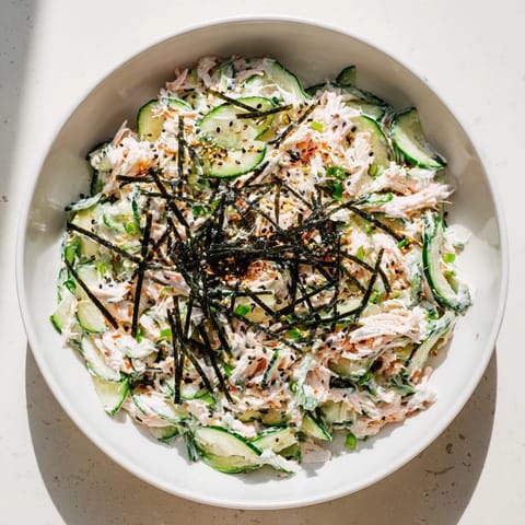 Vibrant California Roll Cucumber Salad topped with nori strips, scallions, and pickled ginger for a fresh Japanese-American appetizer.