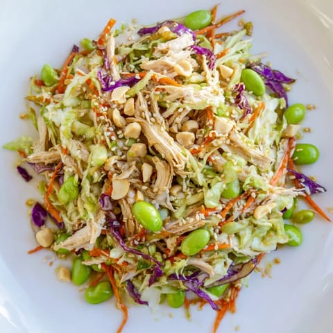 Vibrant Edamame Crunch Chicken Salad in a white bowl, topped with cashews and sesame seeds, perfect for a healthy lunch.  