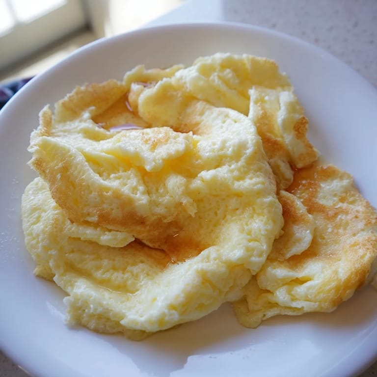 Visualize a plate piled high with light and airy, golden-brown scrambled pancakes.