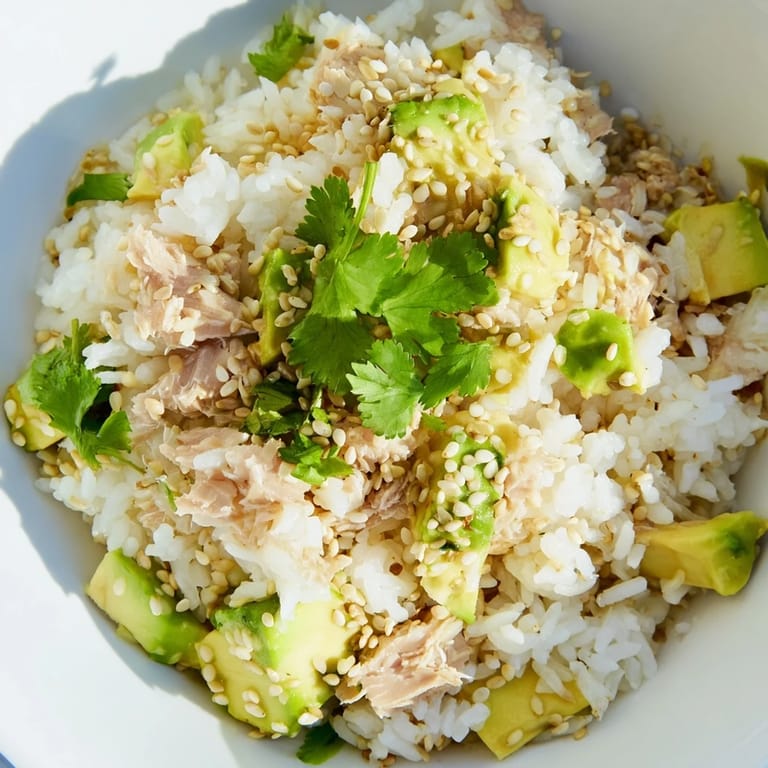 Healthy Tuna Avocado Rice Bowl topped with nori strips and scallions, drizzled with a savory sesame ginger dressing.