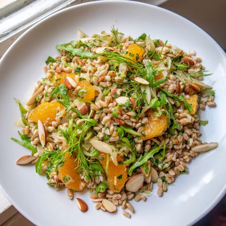 A plated portion of Farro Salad With Fennel, Oranges, and Almonds highlights the contrast between the nutty grains, crisp shaved fennel, juicy citrus, and crunchy toasted almonds, ready to enjoy.