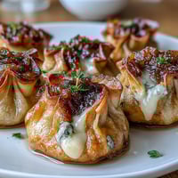 Crispy caramelized French onion soup dumplings filled with gooey Gruyère and topped with fresh chives.