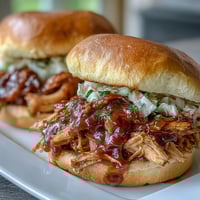 1. Juicy pulled BBQ chicken sandwiches loaded with smoky, tangy barbecue sauce and creamy coleslaw on soft brioche buns.