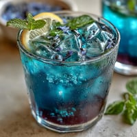 Butterfly Pea Flower Lemonade, a vibrant blue drink turning purple with ice.